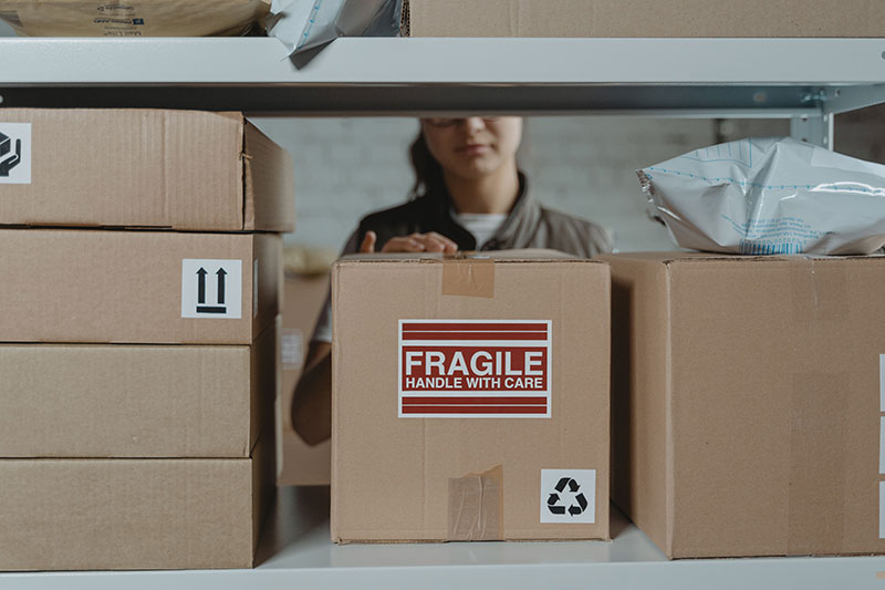 person pulling a fragile box from a shelf of boxes